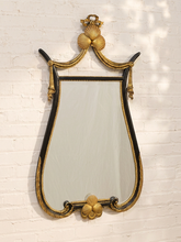 Load image into Gallery viewer, An ornate vintage-style wall mirror with a sculpted gold frame and black accents, mounted on a white painted brick wall.
