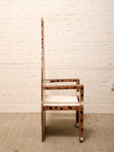 Load image into Gallery viewer, A mid-century modern wooden chair with a high back, upholstered in a brown and black spotted animal print, set against a white brick wall and beige carpet.
