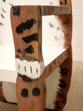 Load image into Gallery viewer, A close-up of a rustic wooden chair featuring a cowhide-patterned backrest and seat, with hand-painted black and white leopard-like markings on the wooden frame.
