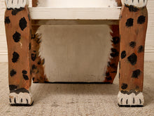 Load image into Gallery viewer, Close-up of the lower portion of a painted wooden chair or stool with animal-print legs, featuring a warm brown base, black spots, and white paw-like feet, set on a beige textured rug.
