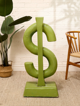 Load image into Gallery viewer, Oversized lime green concrete dollar sign sculpture on a rectangular base with bold graphic Pop Art styling.
