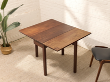 Load image into Gallery viewer, Vintage mid-century walnut drop-leaf dining table with two folding side leaves, slim straight legs, and warm wood finish.
