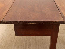 Load image into Gallery viewer, Close-up of a dark brown wooden table showing the tabletop, apron, leg, and visible wear on the edge.
