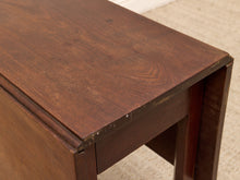 Load image into Gallery viewer, Close-up of a dark brown wooden table corner showing the tabletop grain, edge joint, and part of the leg, with a light beige carpet visible in the background.
