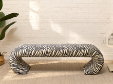 Load image into Gallery viewer, Vintage upholstered bench in black-and-white zebra print with rounded ends, low legs, and brass-tone nailhead trim.
