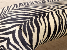 Load image into Gallery viewer, Close-up of a zebra-patterned fabric cushion or upholstered furniture piece, showing bold black and off-white stripes with a soft textured surface.
