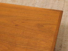 Load image into Gallery viewer, Close-up of a warm medium-brown wooden tabletop corner showing the wood grain and finish, with a light woven rug visible in the background.

