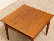 Load image into Gallery viewer, A square wooden coffee table with a warm medium-brown finish and visible wood grain, shown on a textured beige rug.
