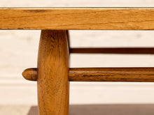 Load image into Gallery viewer, Close-up detail of a mid-century modern wooden table leg with a turned end cap and a horizontal stretcher bar, showing warm medium-brown wood grain.
