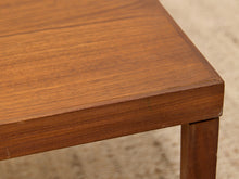 Load image into Gallery viewer, Close-up of a wooden table corner showing the rich medium-brown wood grain and a matching leg, set against a softly blurred beige carpet background.
