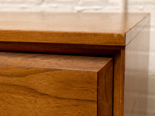 Load image into Gallery viewer, Close-up of a wooden furniture piece showing the top surface, drawer front, and corner joint against a light brick wall background.
