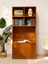 Load image into Gallery viewer, Vintage Danish modern teak wall unit with open upper shelving, warm wood grain, and lower sliding cabinet doors with square wood pulls.
