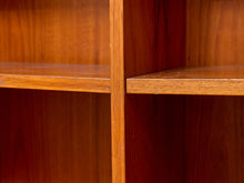 Load image into Gallery viewer, Close-up of a wooden bookshelf with warm medium-brown wood grain, showing the corner joint between two shelves and the vertical divider.
