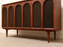 Load image into Gallery viewer, Mid-century modern wooden sideboard cabinet with six arched wire mesh doors and tapered legs, shown against a white brick wall and textured carpet.
