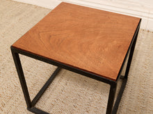 Load image into Gallery viewer, A square side table with a warm brown wood-grain top and a black metal frame, shown on a textured beige rug.

