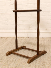 Load image into Gallery viewer, A dark brown wooden stand with twisted legs and a top shelf, photographed indoors against a white brick wall and light woven rug.

