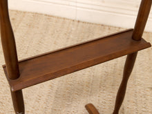 Load image into Gallery viewer, Close-up of a dark brown wooden rocking chair showing the seat, backrest supports, and part of the curved rockers on a textured beige carpet.
