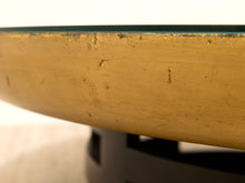 Load image into Gallery viewer, Close-up of a distressed gold table edge with a glass top and a dark metal base.

