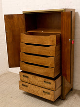 Load image into Gallery viewer, A mid-century modern wooden storage cabinet with an open door, a central stack of five pull-out drawers, and two lower drawers extended outward. The cabinet features a warm brown wood finish with a lighter burl wood front on the bottom drawers and brass hardware.
