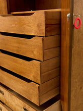 Load image into Gallery viewer, Close-up of a wooden dresser or cabinet with multiple drawers pulled out, showing warm medium-brown wood grain and a dark wood door frame with a small red coiled cord hanging on the right.
