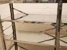 Load image into Gallery viewer, A close-up of a polished stainless steel shelving unit with three tiers, set against a white painted brick wall.

