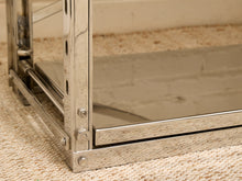 Load image into Gallery viewer, Close-up of a polished chrome metal frame corner with a glass panel, resting on a beige woven rug.
