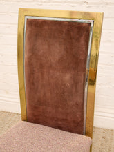 Load image into Gallery viewer, A close-up of a mid-century modern chair featuring a tall, rectangular backrest upholstered in brown suede, surrounded by a polished gold-tone metal frame, with a textured pinkish-beige seat cushion visible at the bottom.
