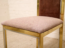 Load image into Gallery viewer, A close-up of a modern dining chair featuring a textured mauve-pink upholstered seat cushion and a dark brown upholstered backrest, supported by a polished gold metal frame.
