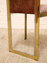 Load image into Gallery viewer, Close-up of a modern chair leg featuring a polished gold metal frame, a brown velvet upholstered backrest, and a textured light pink seat cushion on a woven beige rug.

