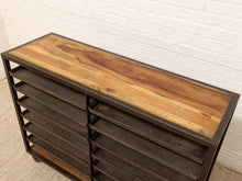 Load image into Gallery viewer, A rolling storage cabinet with a rustic wood top and dark metal frame, featuring multiple pull-out drawers on the left side, photographed against a white brick wall.
