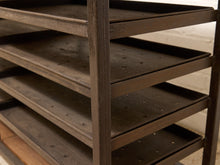 Load image into Gallery viewer, A close-up of a dark brown metal shelving unit with multiple tiers and a vertical support frame, set against a light neutral background.
