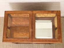 Load image into Gallery viewer, A wooden display cabinet with two glass-front doors, shown from above against a white brick wall and woven rug.
