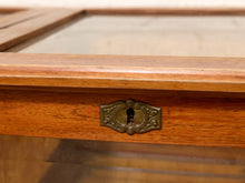Load image into Gallery viewer, Close-up of a wooden display case or cabinet door with a glass panel and an ornate brass keyhole.
