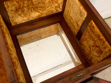 Load image into Gallery viewer, A close-up view of a wooden display case or coffin with a glass top panel and plush gold velvet lining.
