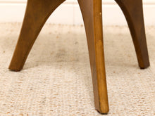 Load image into Gallery viewer, Close-up of a wooden stool or table leg resting on a textured beige woven rug, with a white wall in the background.
