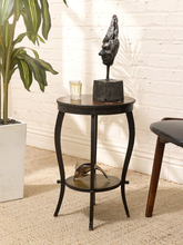 Load image into Gallery viewer, A small round dark wood and metal side table with curved legs, styled in a room setting with a potted plant, a black sculptural bust, and a small glass candle holder on top.
