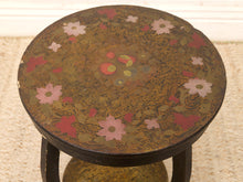 Load image into Gallery viewer, A round wooden side table with a dark brown base and hand-painted floral motifs in pink, red, and green, set on a textured beige rug.
