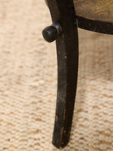 Load image into Gallery viewer, Close-up of a dark painted wooden table leg with a turned pedestal base, resting on a textured beige woven rug.
