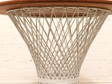 Load image into Gallery viewer, Close-up of a table base with a circular medium-brown wood top and a conical, open-weave structure made of light gray string or rope, set against a white painted brick wall.
