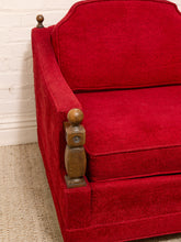 Load image into Gallery viewer, A close-up of a red upholstered armchair with wooden turned post details on the armrests, set against a white brick wall and beige rug.
