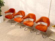 Load image into Gallery viewer, Four mid-century modern velvet swivel armchairs in burnt orange, arranged in a row against a white brick wall on a beige carpet.
