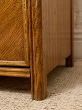 Load image into Gallery viewer, Close-up of a medium brown wooden furniture piece, showing the corner joint, grain, and leg, resting on a textured beige woven rug.
