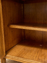 Load image into Gallery viewer, Close-up view of the interior shelves of a wooden bookcase or cabinet, showing a warm medium-brown wood grain finish.
