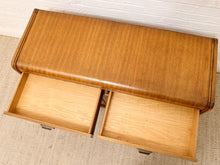 Load image into Gallery viewer, A mid-century modern wooden console table with a curved top, upholstered in warm brown leather, and two open drawers showing light wood interiors, set against a white brick wall and beige carpet.
