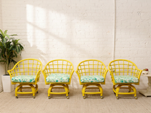 Load image into Gallery viewer, Image 1 of 20: Set of four vintage bright yellow rattan barrel chairs with curved lattice backs and green botanical print cushions
