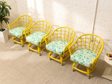 Load image into Gallery viewer, Image 3 of 20: Set of four vintage bright yellow rattan barrel chairs with curved lattice backs and green botanical print cushions
