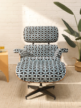 Load image into Gallery viewer, A mid-century modern lounge chair with a black, white, and gray geometric patterned fabric, set against a white brick wall with a potted plant and a small wooden side table.
