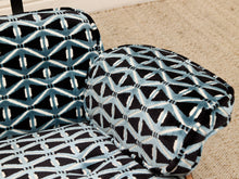 Load image into Gallery viewer, Close-up of upholstered chair cushions with a black, white, and blue geometric lattice pattern, set against a beige carpeted floor.
