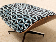 Load image into Gallery viewer, A mid-century modern lounge chair with a curved wooden shell and a black upholstered seat cushion featuring a light blue and white geometric pattern, shown on a beige textured rug.
