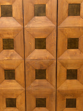 Load image into Gallery viewer, Close-up of a wooden cabinet or door with a geometric pattern of raised octagonal panels and dark square inset details.

